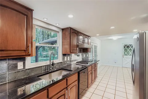 a kitchen with granite countertop a sink a counter top space and cabinets