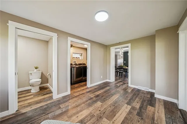 a view of a hallway with wooden floor and a bathroom