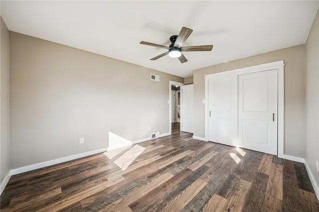 a view of empty room with wooden floor and ceiling fan