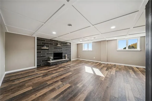 an empty room with wooden floor a fireplace and windows