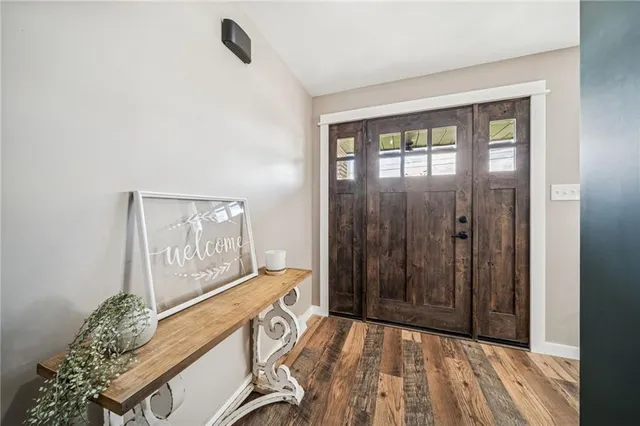 a view of a hallway with wooden floor and a bathroom
