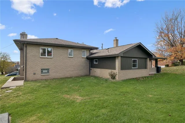 a white house that has a small yard and trees in front of it