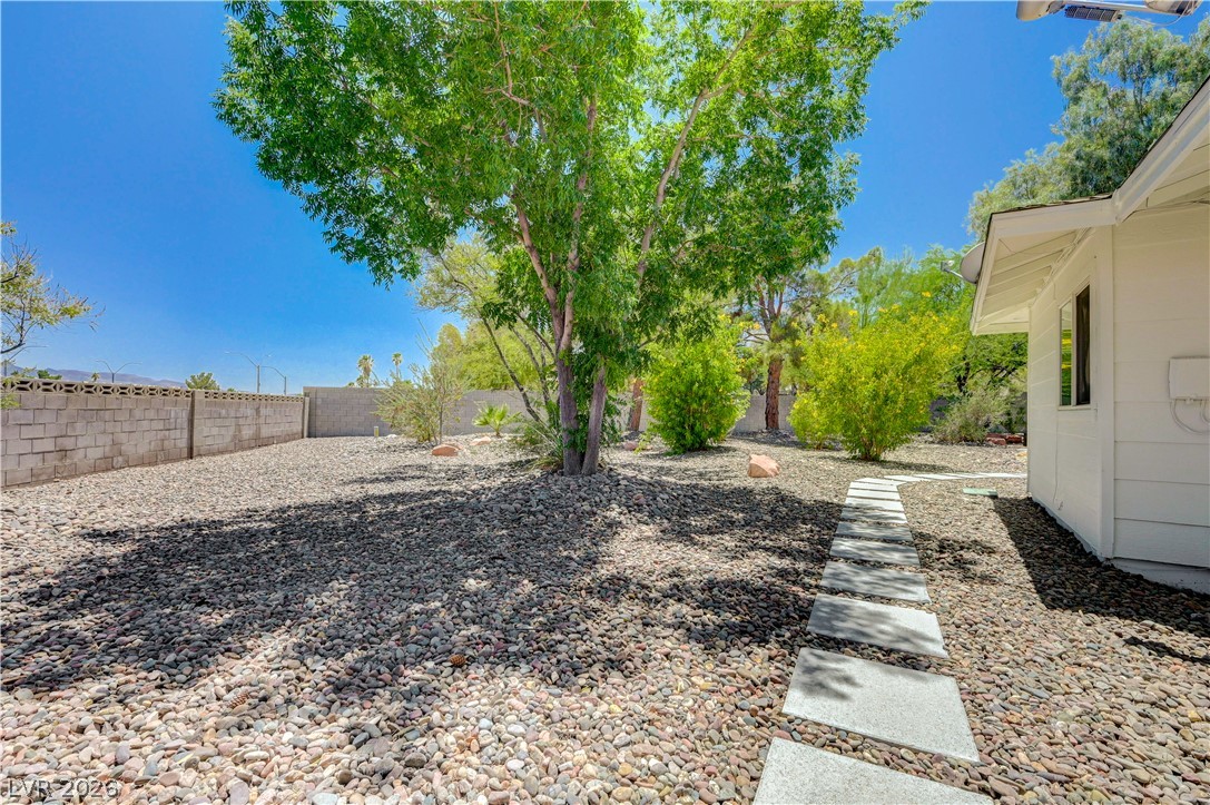 7631 Bermuda Road Las Vegas, NV 89123 - Photo 49 of 64 A well-maintained side yard with natural rock landscaping and a clear paver path leading to the home.