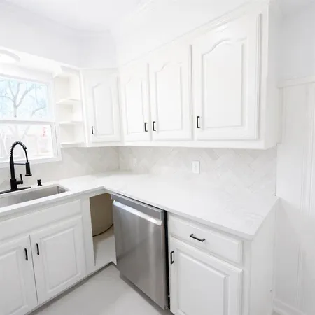 a kitchen with white cabinets appliances and a sink