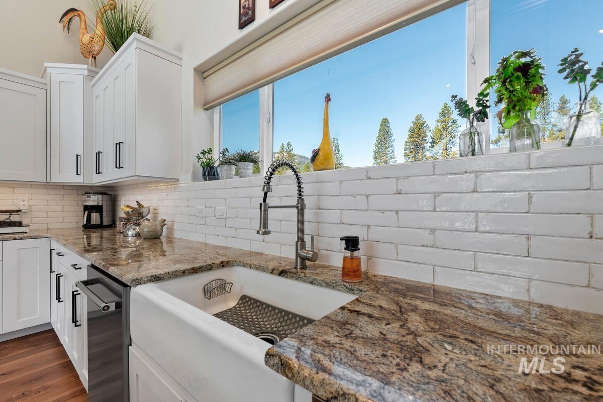 21 Open Road Garden Valley, ID 83622 - Photo 12 of 49 Kitchen with light stone counters, white cabinetry, tasteful backsplash, and wood finished floors