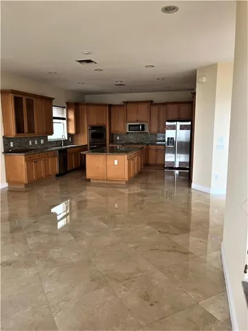 a kitchen with stainless steel appliances kitchen island granite countertop a sink and cabinets