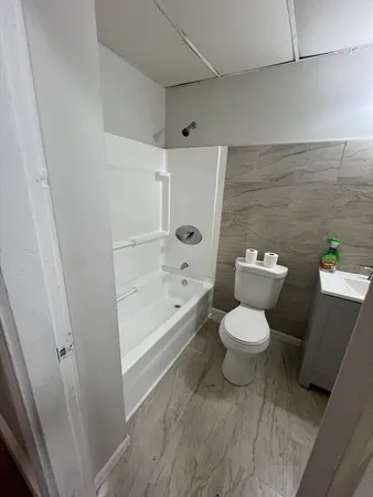 a white toilet sitting next to a bath tub and a shower