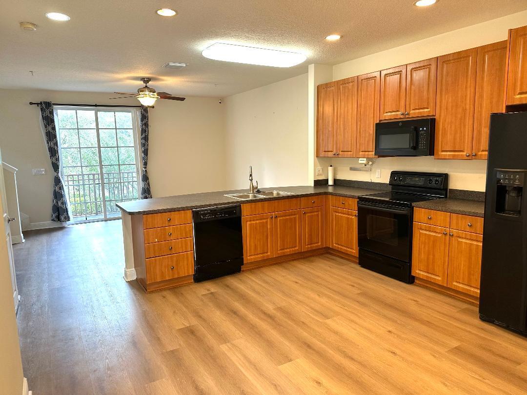 808 University Boulevard Jupiter, FL 33458 - Photo 6 of 16 a kitchen with stainless steel appliances granite countertop a sink dishwasher stove and refrigerator with wooden floor