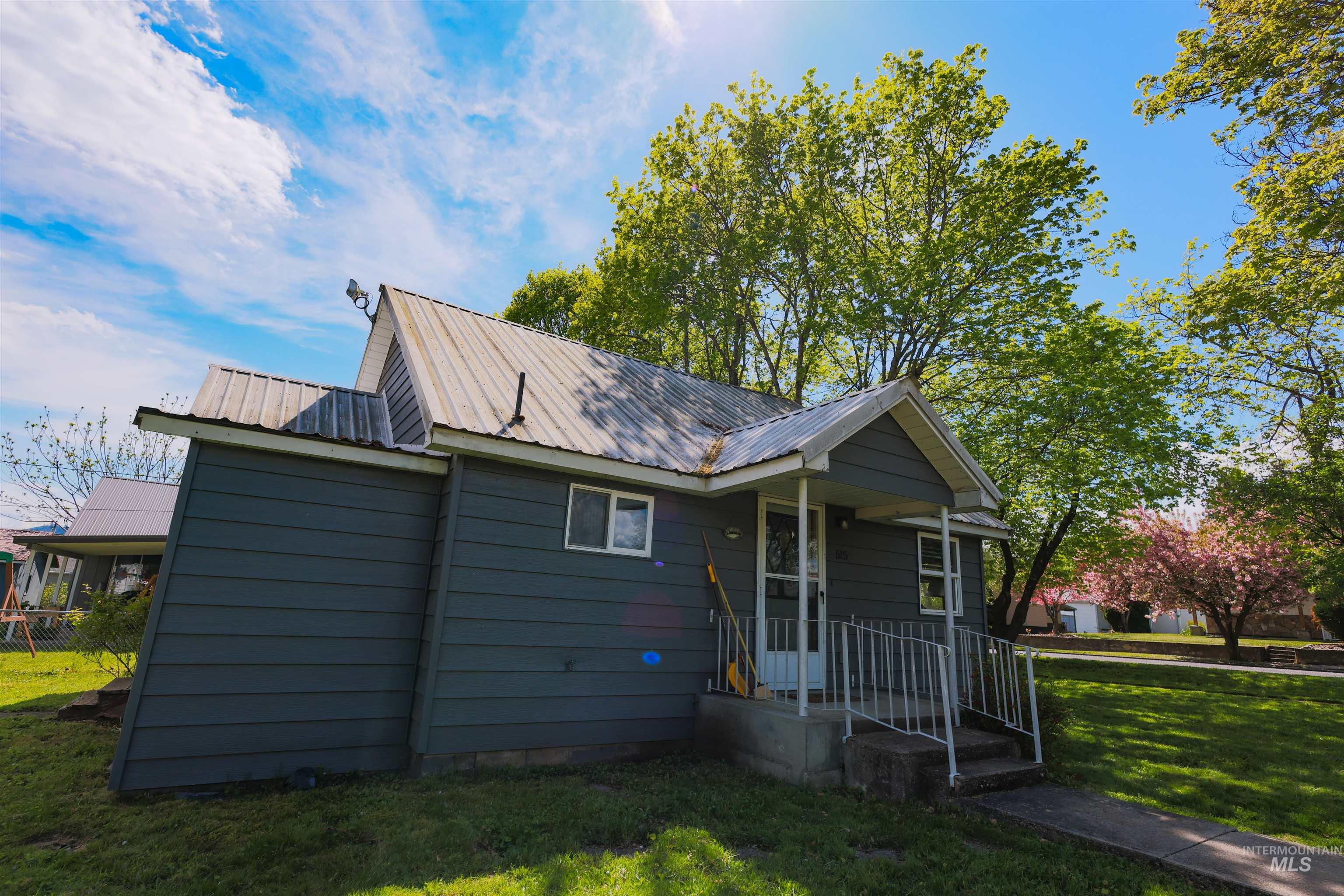 Exterior featuring dark gray siding, a metal roof, and a covered porch entry