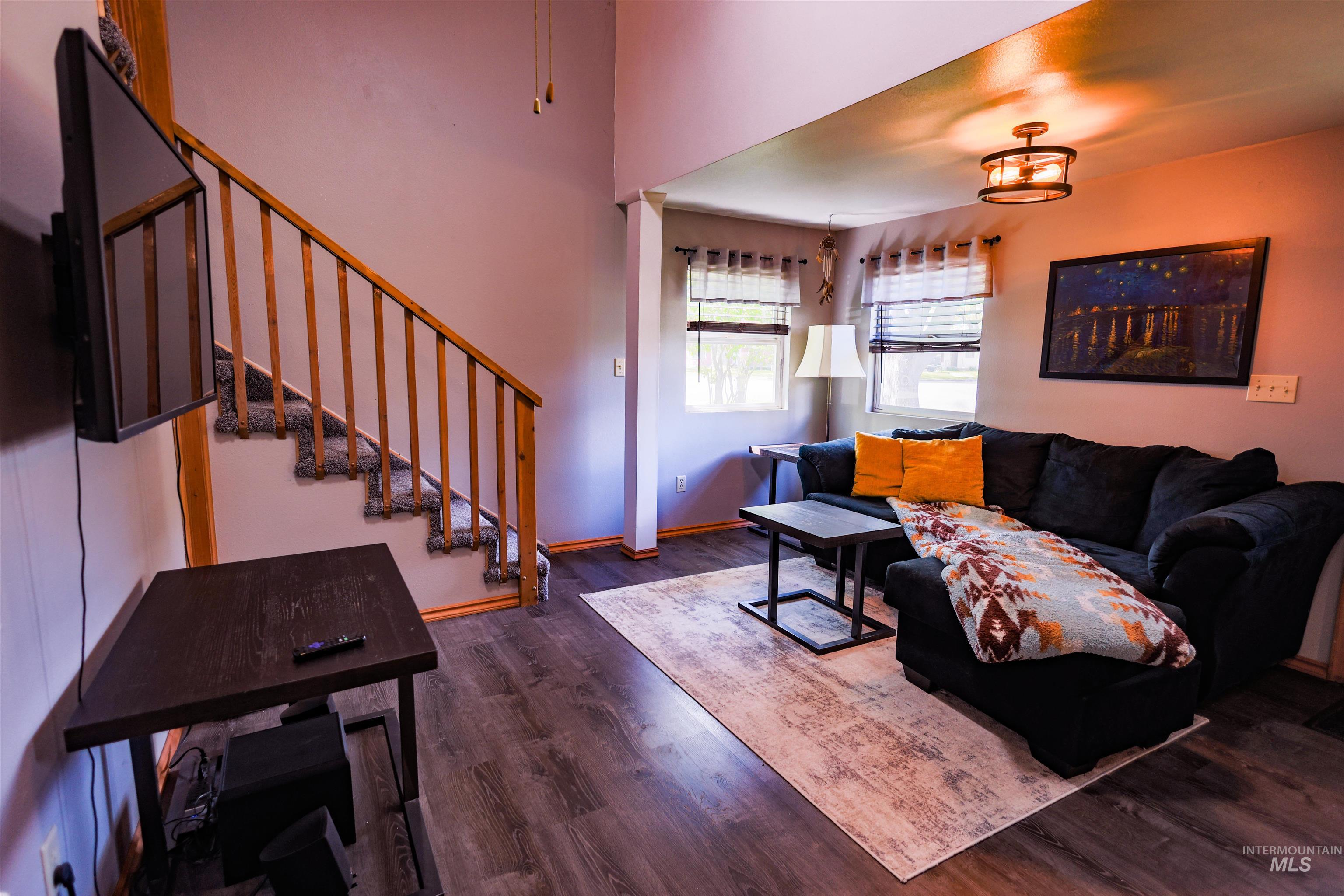 515 8th Street Kamiah, ID 83536 - Photo 13 of 31 Living area featuring wood-finish flooring, a carpeted staircase with wood banister, and a semi-flush mount ceiling fixture