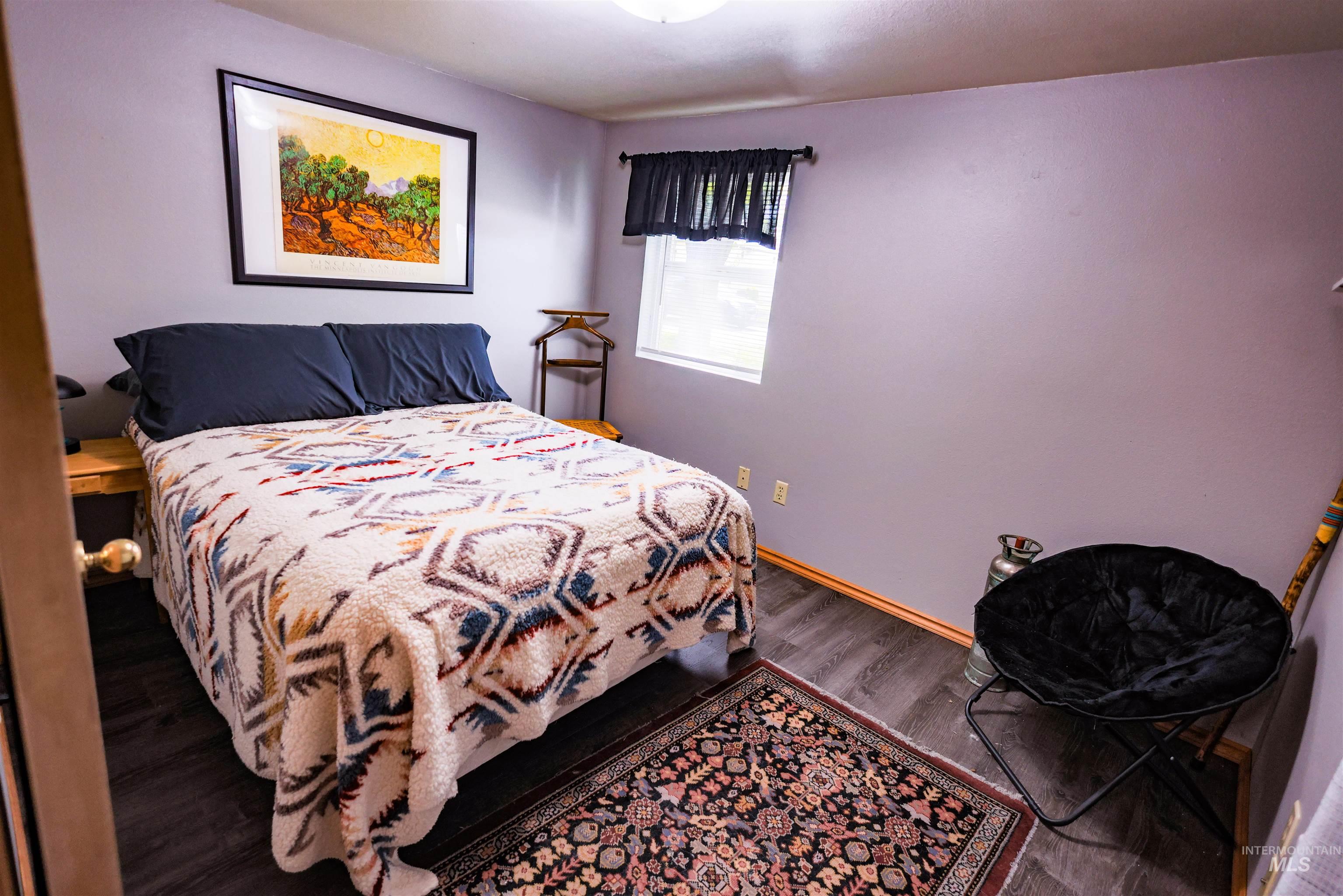 515 8th Street Kamiah, ID 83536 - Photo 17 of 31 Bedroom featuring wood-finish flooring, a single window with curtain, and a ceiling-mounted light fixture