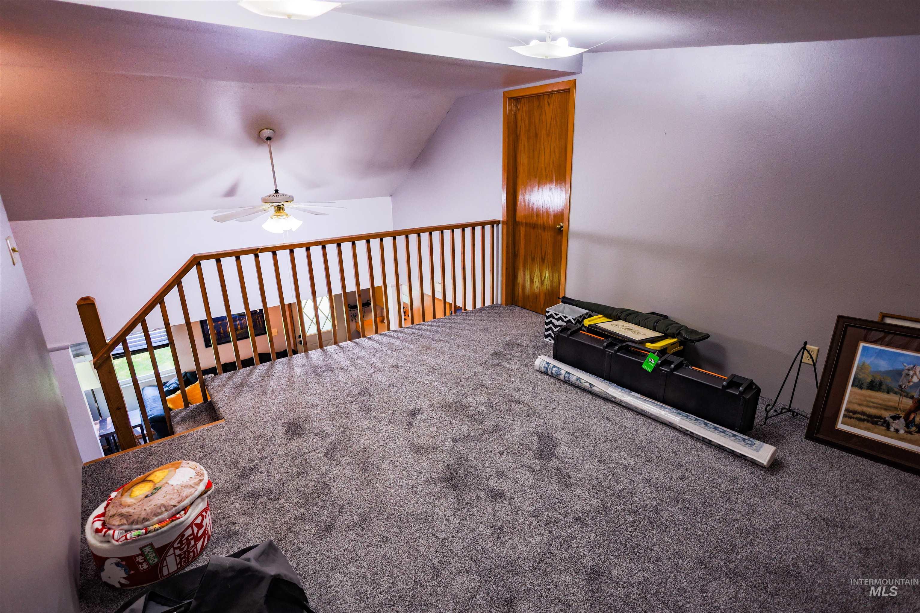 515 8th Street Kamiah, ID 83536 - Photo 20 of 31 Carpeted loft area featuring a wood-finish staircase railing and a vaulted ceiling with a ceiling fan