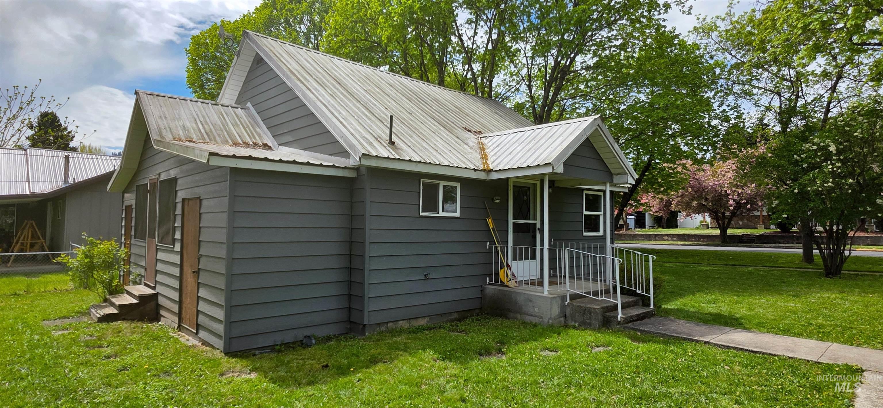 515 8th Street Kamiah, ID 83536 - Photo 30 of 31 Gray siding exterior with a metal roof and a covered front porch featuring white railings