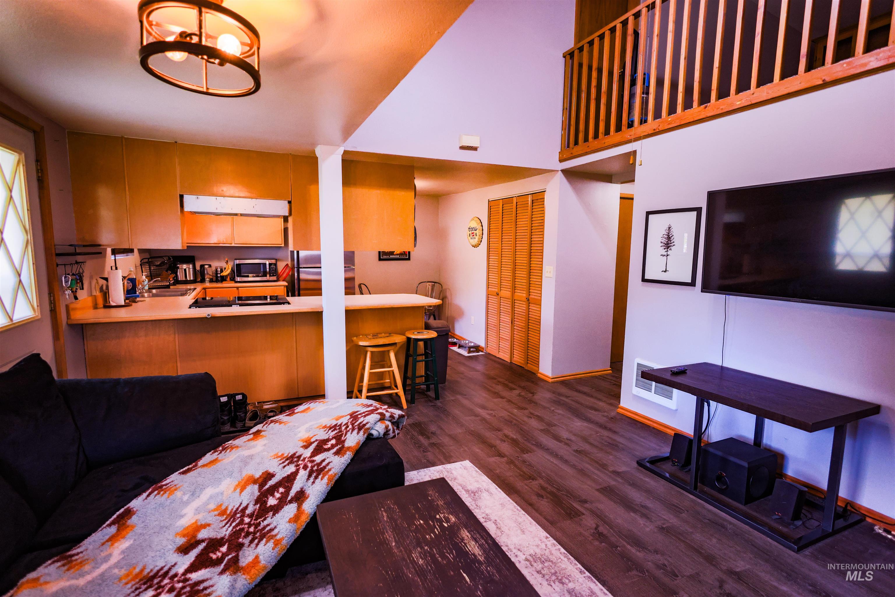 515 8th Street Kamiah, ID 83536 - Photo 7 of 31 Open-concept living area featuring wood-finish flooring, a kitchen with light wood cabinetry, a breakfast bar, and a loft overhead with wood railings