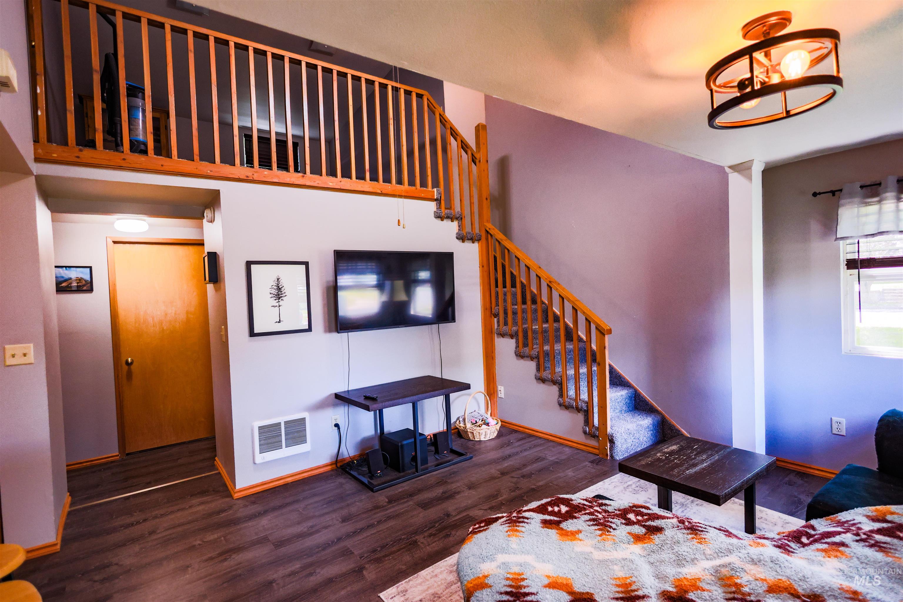515 8th Street Kamiah, ID 83536 - Photo 8 of 31 Living area featuring wood-finish flooring, a carpeted staircase with wood banister, and an overhead loft with wood railing