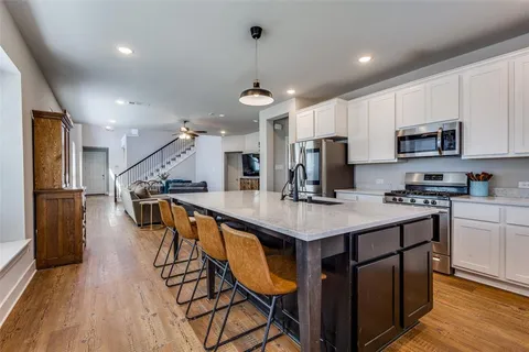 a kitchen with stainless steel appliances a table chairs wooden floors and a view of living room
