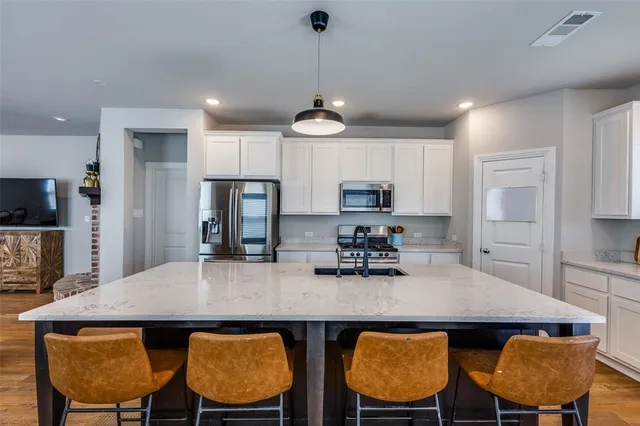 a kitchen with stainless steel appliances granite countertop a dining table chairs and refrigerator