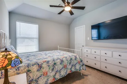 a bedroom with a bed a dresser and a flat screen tv