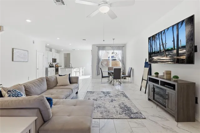 a living room with stainless steel appliances furniture a rug and a kitchen view