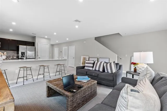 a living room with furniture and a view of kitchen