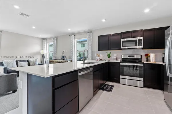 a kitchen with stainless steel appliances granite countertop a sink and stove top oven with wooden floor