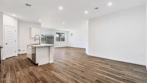 a kitchen with granite countertop white cabinets and wooden floor