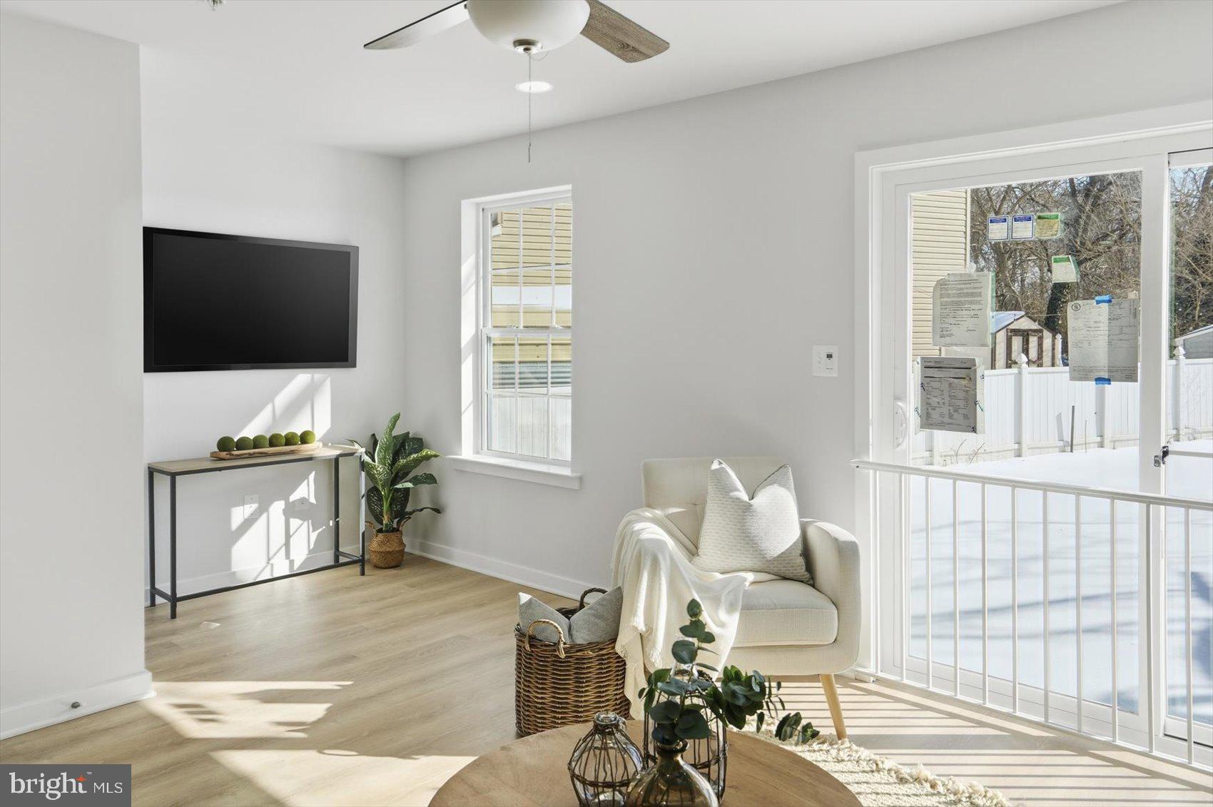 715 Hammonds Lane Baltimore, MD 21225 - Photo 2 of 29 a living room with furniture a flat screen tv and a floor to ceiling window