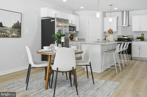a kitchen with stainless steel appliances kitchen island granite countertop a dining table chairs and a refrigerator