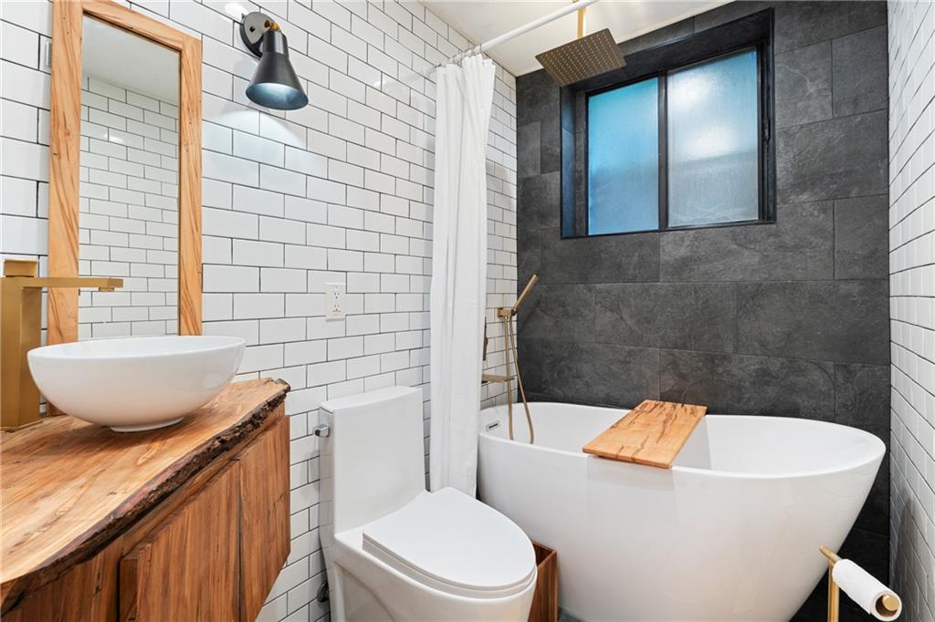 880 Glendale Terrace Northeast, Unit 9 Atlanta, GA 30308 - Photo 16 of 18 a bathroom with a granite countertop bathtub sink vanity mirror and toilet
