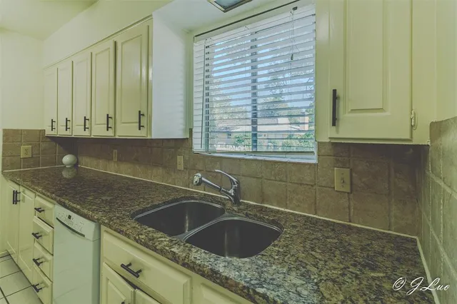 a kitchen with granite countertop a sink and cabinets