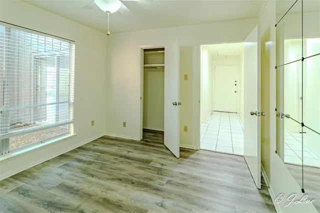 a view of an empty room with window and wooden floor