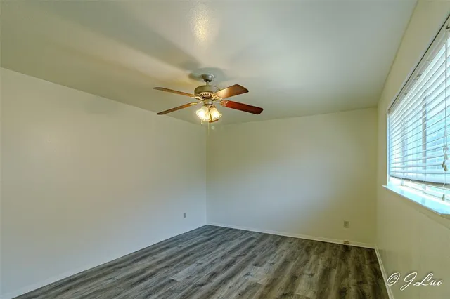 an empty room with windows and fan