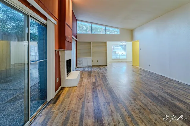 a view of a hallway with wooden floor and a bathroom