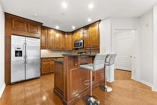 a kitchen with stainless steel appliances granite countertop a refrigerator a stove top oven a sink with island and chairs