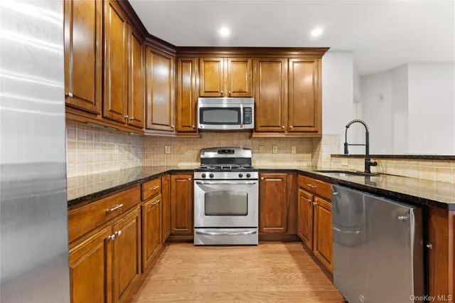 a kitchen with stainless steel appliances granite countertop a sink a stove and cabinets