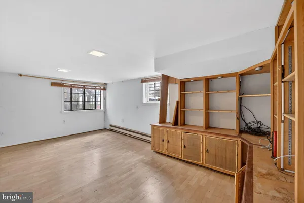 a view of an empty room with window and hardwood floor