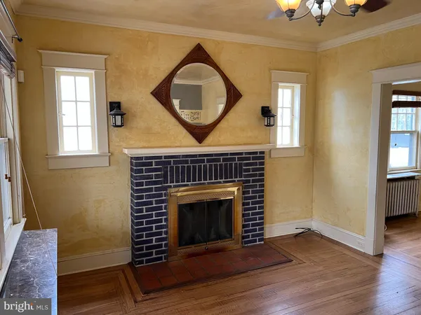 an empty room with wooden floor a fireplace and a window