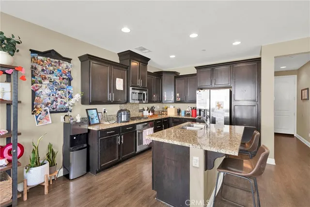 a kitchen with stainless steel appliances granite countertop a refrigerator a sink dishwasher and wooden cabinets with wooden floor