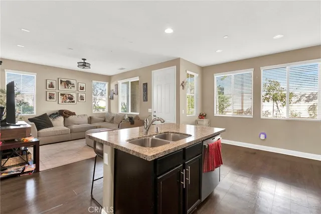 a living room with kitchen island granite countertop a sink and a large window with wooden floor