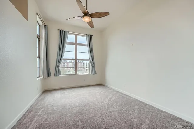 an empty room with windows and fan