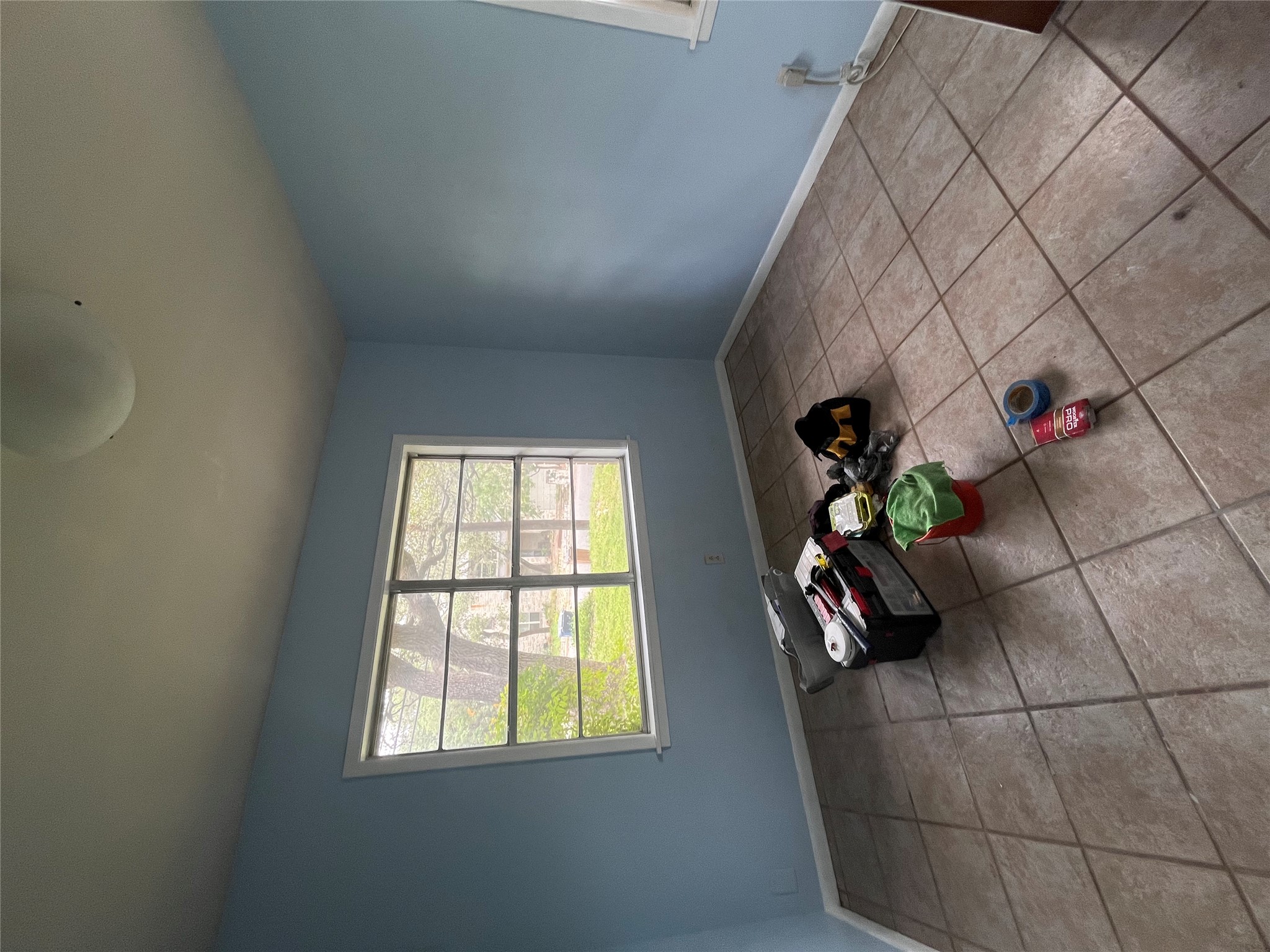 1607 Lightsey Road, Unit A Austin, TX 78704 - Photo 12 of 17 Spacious room featuring tile flooring, light blue wall paint, a large window with exterior landscaping visible, white trim, and a ceiling-mounted light fixture