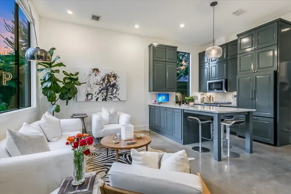 a living room with furniture kitchen view and a chandelier