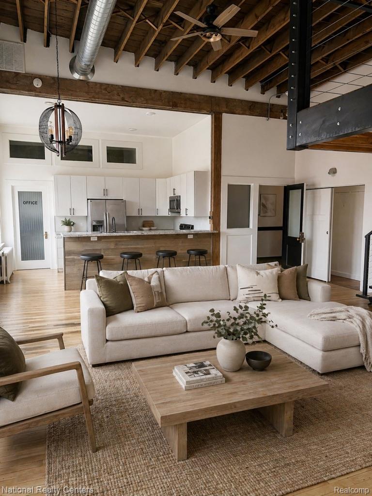 17 West Lawrence Street, Unit 2D Pontiac, MI 48342 - Photo 6 of 12 Open-concept living space featuring wood-finish flooring, exposed beam ceiling with ductwork, and a contemporary spherical pendant light