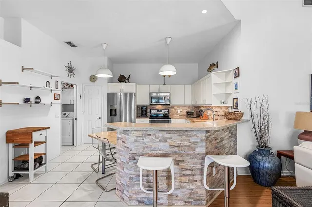 a kitchen with kitchen island granite countertop stainless steel appliances a stove refrigerator sink and cabinets