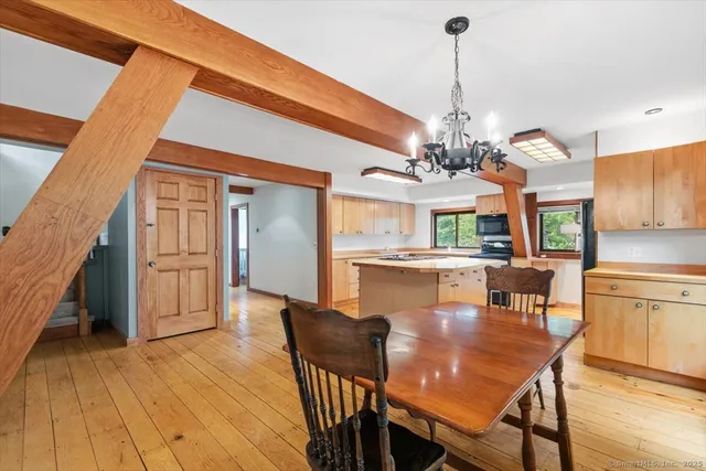 a dining room with wooden floor a chandelier a wooden table and chairs