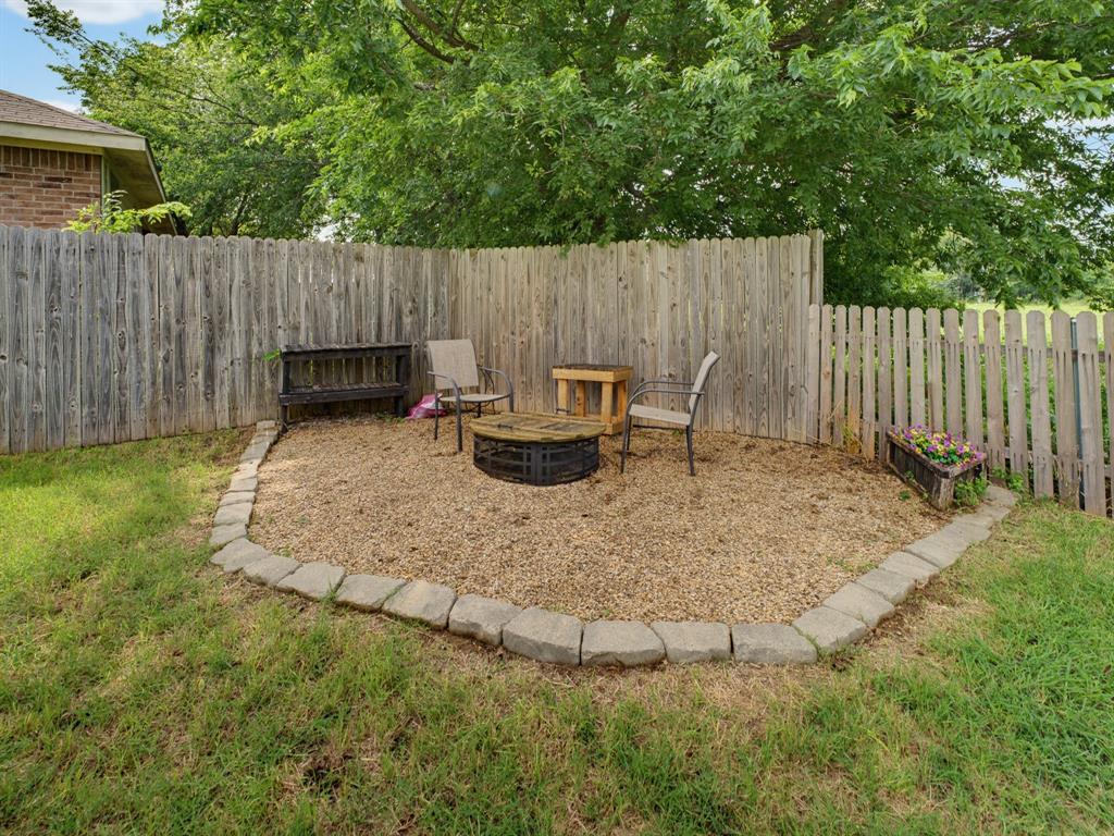 600 Stirling Road Rhome, TX 76078 - Photo 30 of 38 Landscaped gravel patio area bordered by stone pavers and surrounded by a wood privacy fence