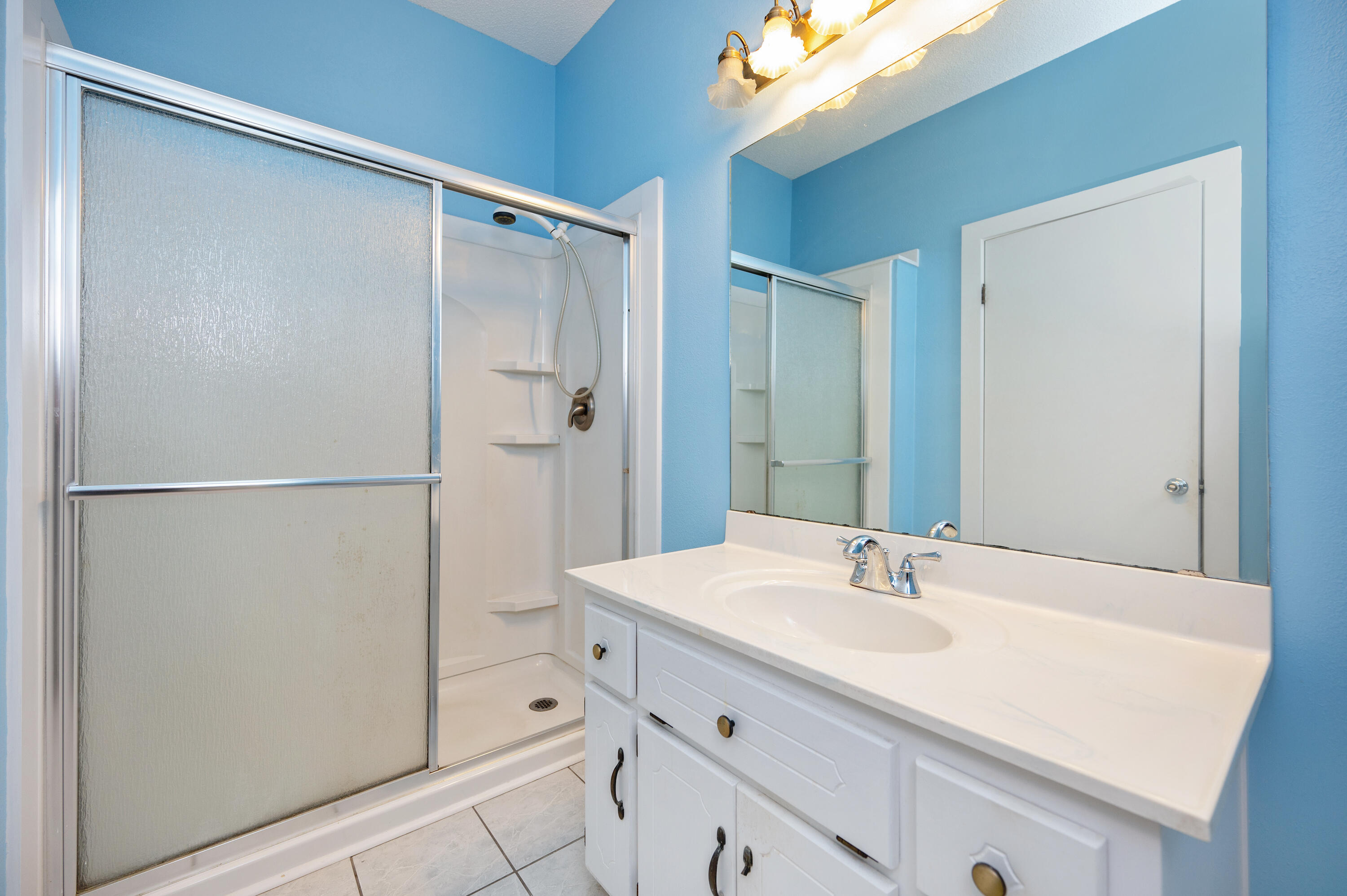 6433 Old River Road Baker, FL 32531 - Photo 18 of 27 a bathroom with a shower sink vanity and mirror