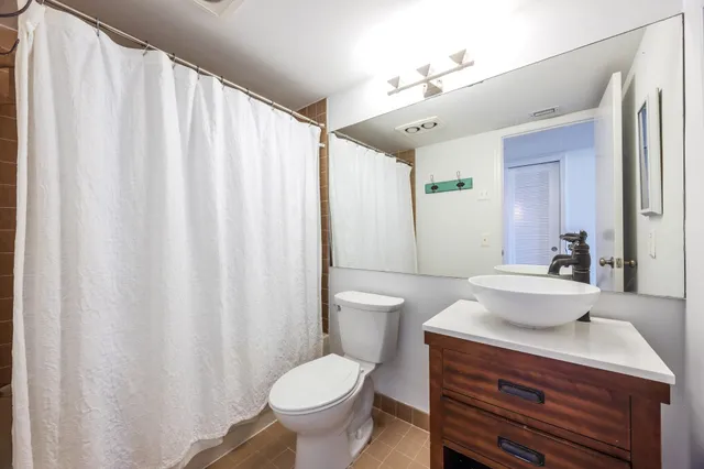 a bathroom with a sink a toilet a mirror and shower curtain