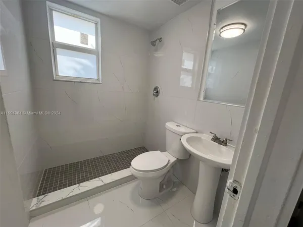 a white toilet sitting next to a bathroom sink and a mirror
