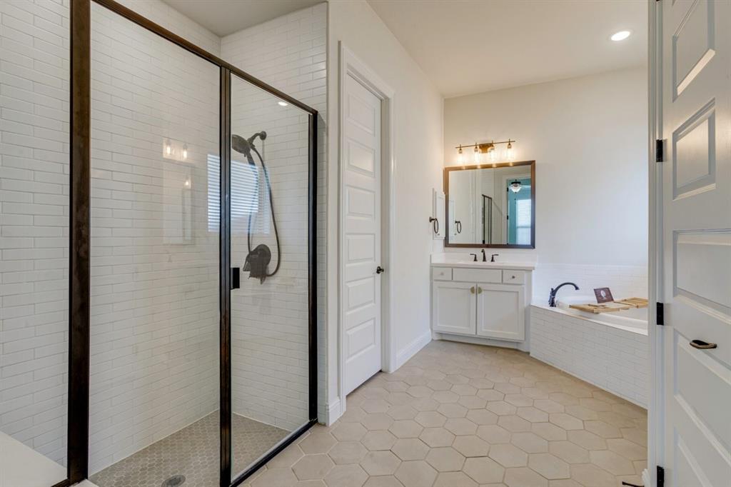 9613 Boulder Pt Road Oak Point, TX 75068 - Photo 21 of 28 Modern bathroom featuring a glass-enclosed shower with white subway tile, a white vanity with an undermount sink, a framed mirror, a built-in bathtub with subway tile surround, and hexagonal floor tiling